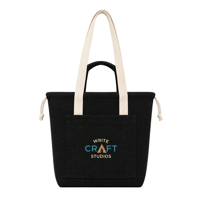 Darby Tote Bag - A black tote bag with long beige handles and a front pocket featuring a logo.