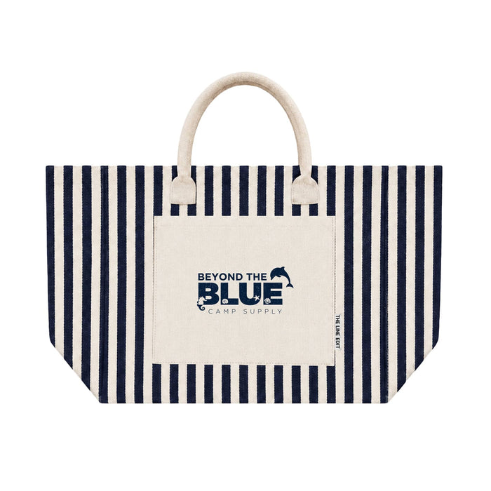 Hampton Tote Bag by The Line Edit. - A striped navy and cream tote bag featuring a front pocket and handles, with a logo on the pocket.