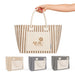 Hampton Tote Bag by The Line Edit. - A striped tote bag in beige, brown, and navy, featuring a front pocket and handles. It has a logo.