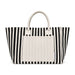 The Weekend Edit - A striped tote bag in black and white with a plain cream-coloured front pocket and handles. It has a logo.