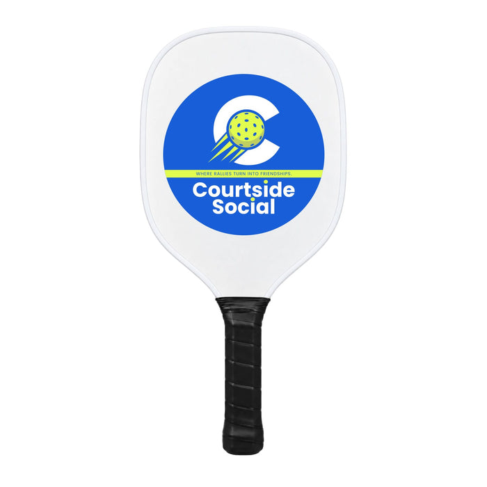 The Play & Graze - A white pickleball paddle with a circular logo featuring a yellow ball and blue accents. It has a black grip.