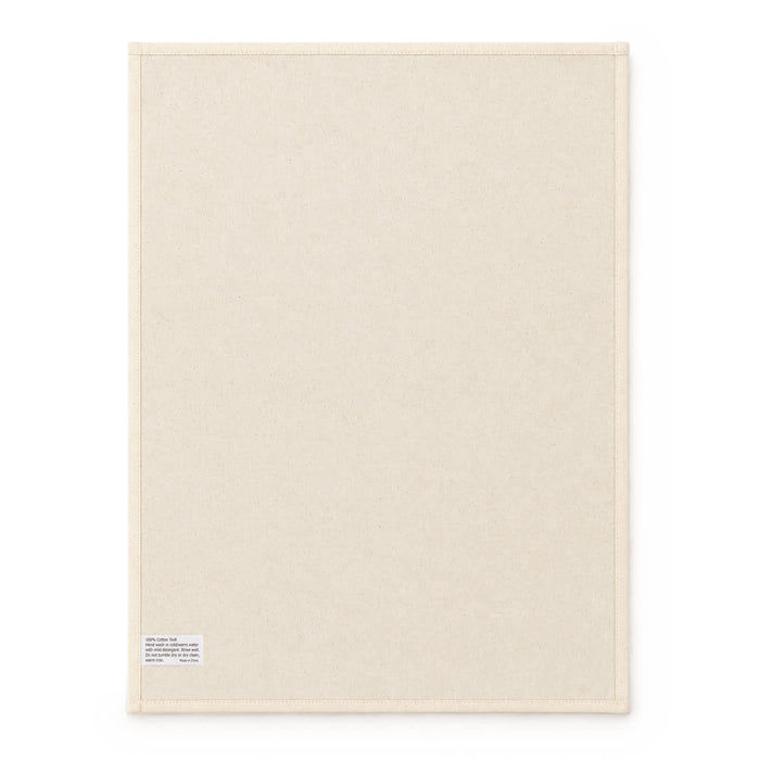 Haven Large Cotton Tea Towel - A large cream cotton tea towel featuring a plain design and a small label in one corner.