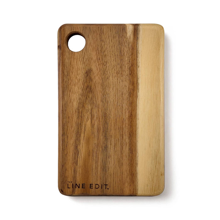The Pamper & Entertain Edit - An acacia serving board in warm brown tones, featuring a circular cut-out and a logo on the side.