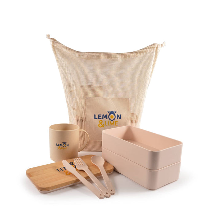 Eco Pack - A beige mesh bag with a logo, containing a mug, two food containers, a bamboo tray, and cutlery in soft pink.