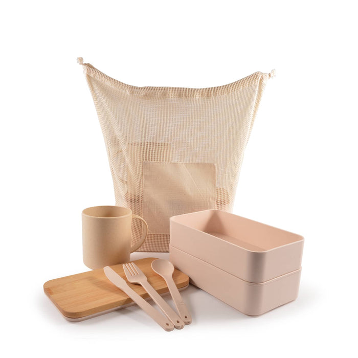Eco Pack - A mesh bag in cream holds a cream mug, wooden cutting board, pink lunch boxes, and pink cutlery.