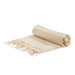 The Weekend Edit - A rolled beige and cream striped picnic blanket with fringed edges, featuring a simple design. It has a logo.