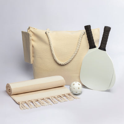 The Courtside Carry - A drink bottle, two paddles, a ball, a towel, and a cream tote bag, all featuring a simple design.