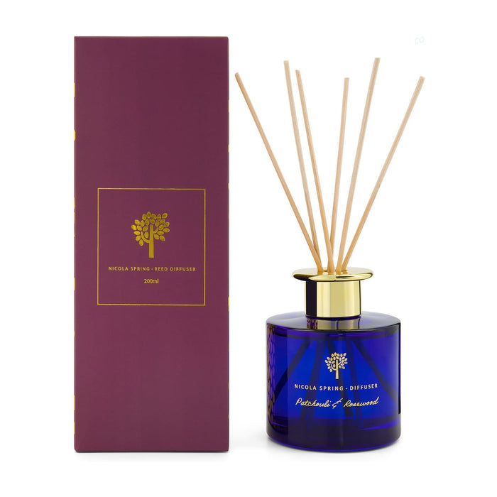 The Mindful Moment - A reed diffuser with a blue glass bottle, gold lid, and bamboo reeds, packaged in a purple box.