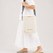 Pavilion Cooler by The Line Edit. - A cream cooler bag carried over the shoulder, featuring a branding logo and set against a neutral background.