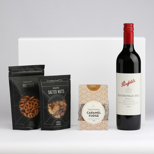The Perfect Pairing - A drink bottle of red wine accompanied by packets of salted nuts, pretzels, and caramel fudge. All items are elegantly arranged.