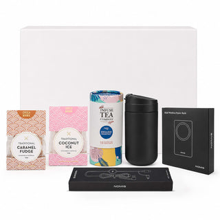 The Modern Essential Gift Set - A drink bottle, tea canister, and assorted sweets in pink and black packaging, alongside a power bank, all in an unlabelled box.