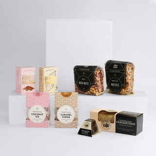 The Big Indulge - A selection of snacks including marshmallows, drink mix, beer nuts, pretzels, coconut ice, caramel fudge, and crackers, all in various packaging.