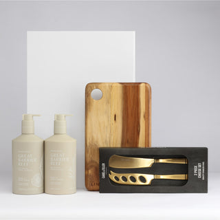 The Pamper & Entertain Edit - A wooden chopping board, two beige pump bottles, and a boxed set of gold-coloured utensils.