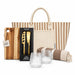 The Weekend Edit - A striped tote bag, a wooden cheese board, a cheese knife set, two clear glasses, and a patterned blanket.