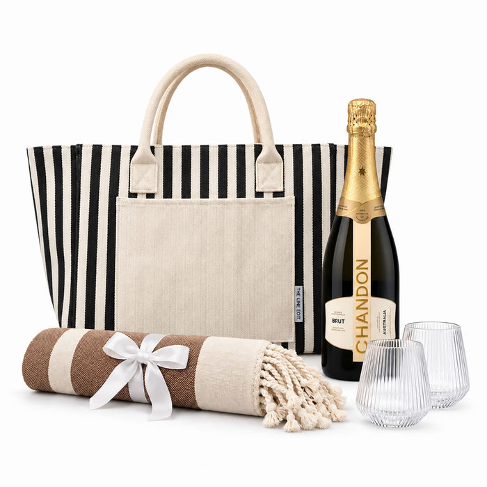 The Sun & Sip Gift Set - A striped tote bag, a bottle of sparkling wine, two glasses, and a rolled blanket with a ribbon.