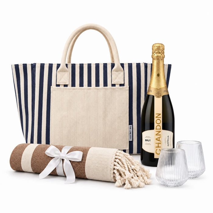 The Sun & Sip Gift Set - A striped tote bag, a bottle of Chandon Brut, two glasses, and a rolled blanket with a ribbon.