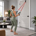 Anywhere Resistance Fitness Set - A person in a green fitness outfit using red resistance bands attached to a door, in a modern living room setting.