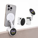 Tutor Maglock Phone Holder - A white phone holder with a black attachment, displaying a logo, mounted on a smartphone and a tabletop.