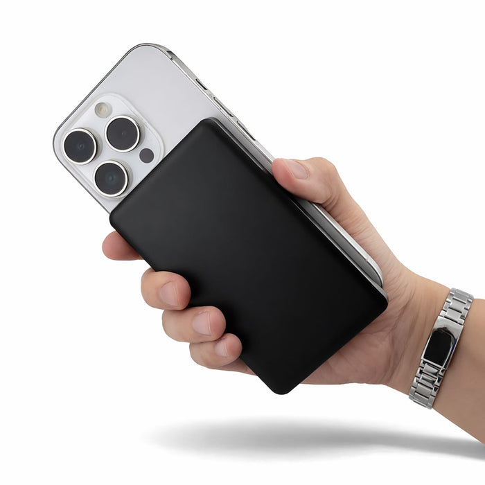 Axial by Nomis Solid State Power Bank - A black power bank held in one hand, with a smartphone in the other. The background is plain.
