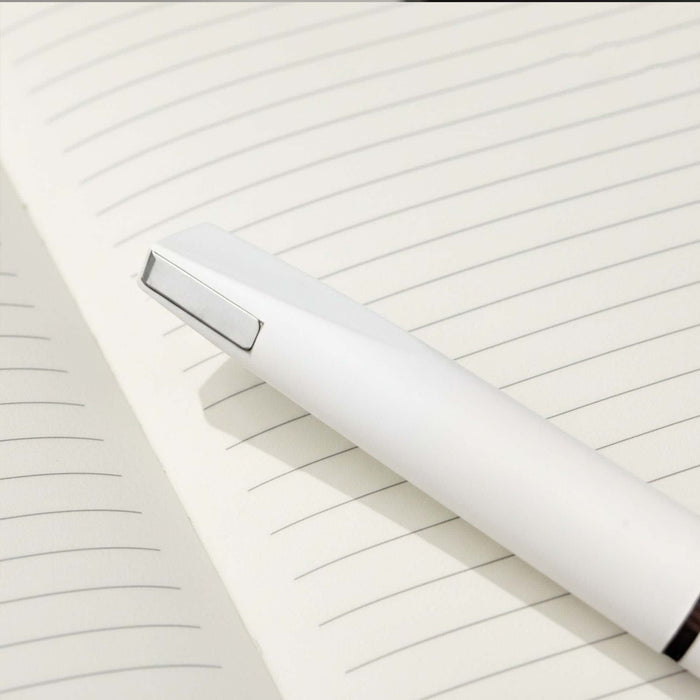 Axel Matte - A white pen rests on a lined notebook page, featuring a sleek design and minimalistic style.