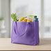 Medium Non Woven Tote - A purple non-woven tote filled with bananas, oranges, asparagus, and a drink bottle. It has two handles.