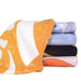 Bath Sheet - A stack of face washers in various colours including orange, blue, and black, featuring vibrant patterns.