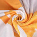 Bath Sheet - A soft face washer in orange and white, featuring a spiral design with a plush texture. It includes a logo.