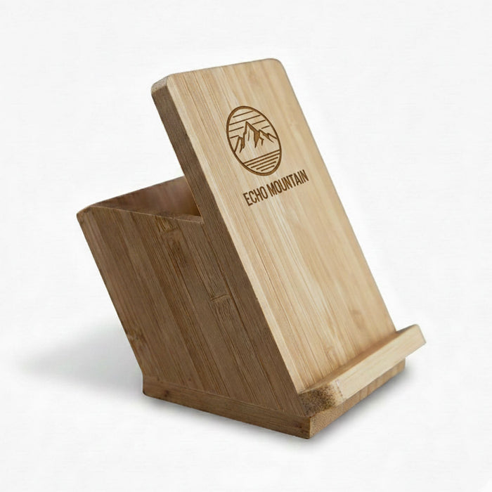 Bamboo Mobile Stand and Pen Holder - A bamboo mobile stand and pen holder with an angled design and a logo on the front.