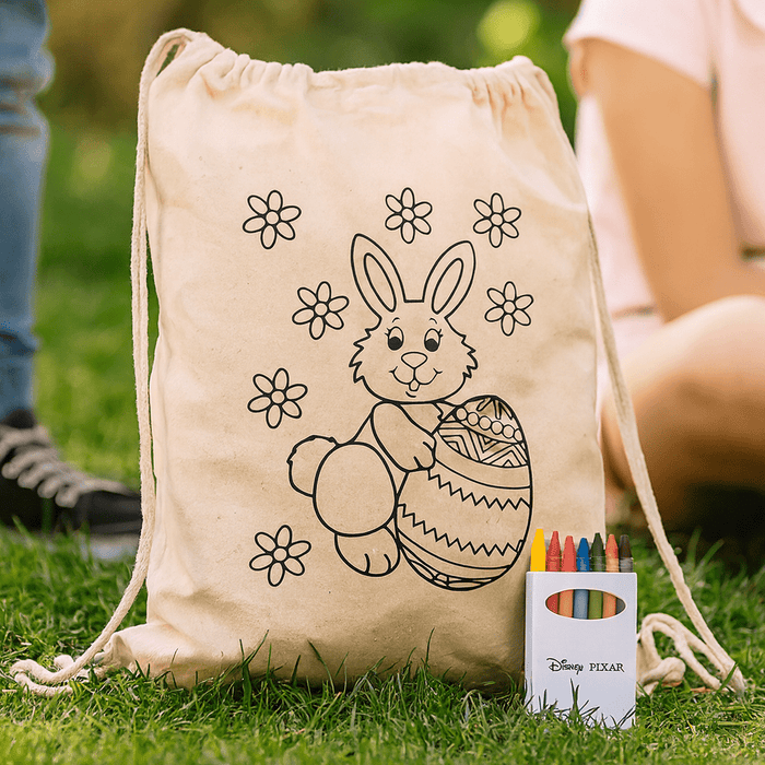 Squiggle Calico Drawstring Bag + Crayon set - A cream drawstring bag featuring a bunny and floral design, accompanied by a crayon set in various colours.