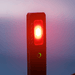 Rechargeable Work Light - A rechargeable work light with a red light and a green indicator, featuring a sleek black design and a logo.
