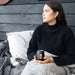 Zen Mirror Finish Mugs (350mL) - A black Zen mirror finish mug with a logo, held by a woman sitting on a couch with a blanket.