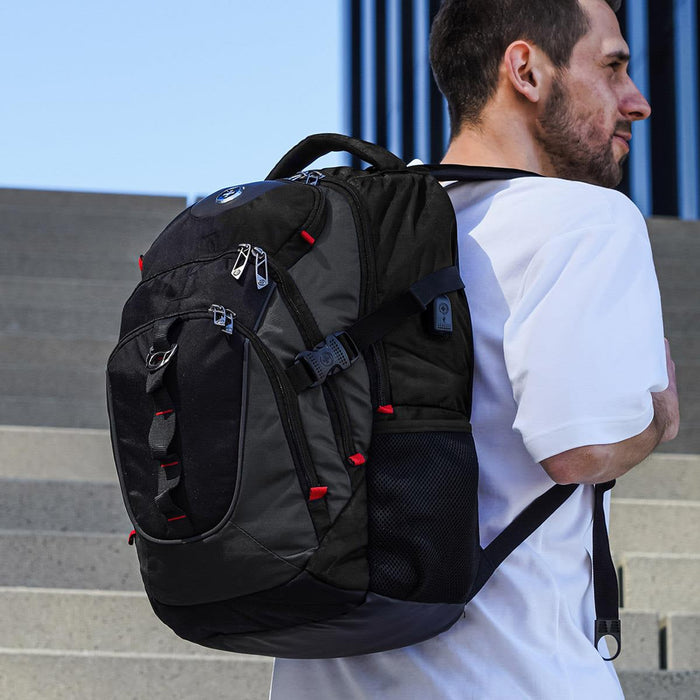 Swissdigital Vector Backpack - A black backpack with red accents is worn on the back of a person standing on steps, featuring multiple compartments and a logo.