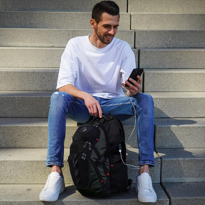 Swissdigital Vector Backpack - A man sits on steps, holding a phone, with a black Swissdigital Vector Backpack beside him.
