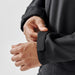 Men's Aleutian Softshell Jacket - A close-up of a man's hands adjusting the cuffs of a black softshell jacket with velcro closures.