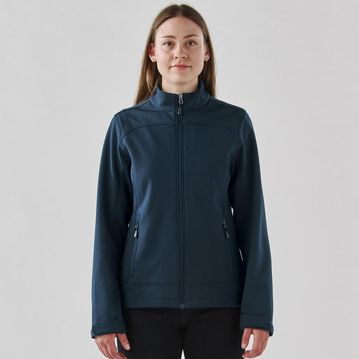 Women's Aleutian Softshell Jacket - A women's softshell jacket in navy blue with a full zipper and side pockets, featuring a branded logo.