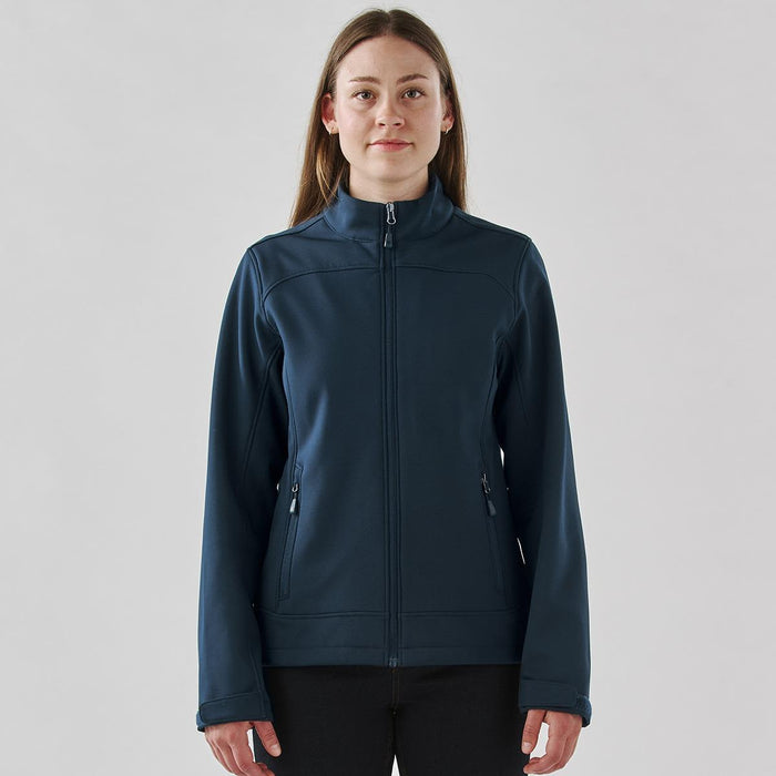 Women's Aleutian Softshell Jacket - A women's softshell jacket in navy blue with a full zipper and side pockets, featuring a branded logo.