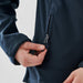 Women's Aleutian Softshell Jacket - A navy women's softshell jacket featuring a zippered pocket. The jacket has a close-up view of the hand and zipper detail.