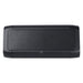 Trekk Outdoor Speaker & Wireless Powerbank - A black outdoor speaker and wireless power bank with a textured front surface and rounded edges. It features a logo.