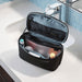 Thule Subterra 2 Toiletry Bag w/ Removable Pouch - A black toiletry bag with a removable pouch, featuring various personal care items inside, displayed on a bathroom countertop.