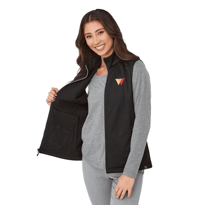 Women's Joris Eco Waterproof Softshell Vest - A woman wearing a black eco waterproof softshell vest, featuring a logo on the chest, with an open front.