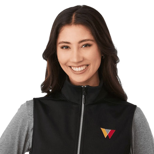 Women's Joris Eco Waterproof Softshell Vest - A black softshell vest featuring a zippered front and a logo. The model wears a grey long-sleeve top underneath.