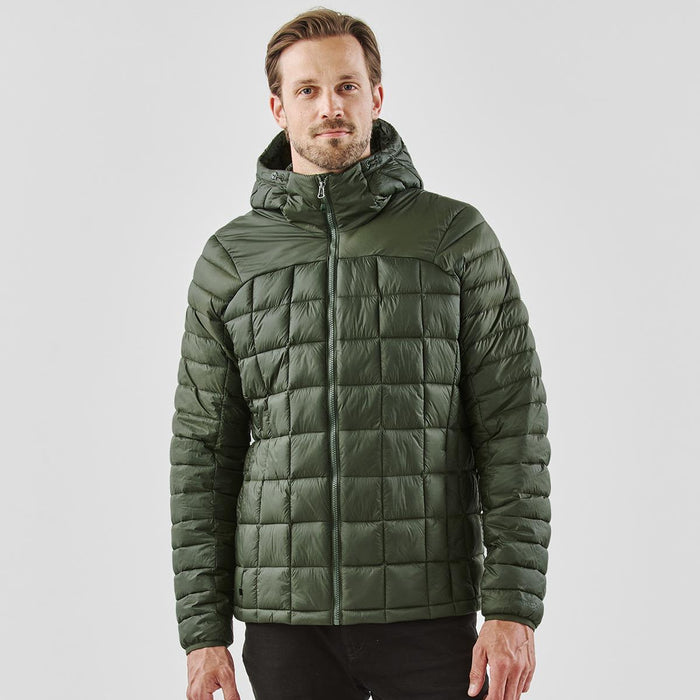 Men's Tundra Thermal Jacket - A man wearing a green puffer jacket with a hood, featuring a quilted design. The jacket has a logo on it.