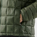 Men's Tundra Thermal Jacket - A puffer jacket in a dark green colour featuring a zip closure and a side pocket with a branded logo.