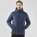 Men's Cascadia Thermal Jacket - A man wearing a navy puffer jacket with a hood, featuring a branding logo. The jacket has a sleek, modern design.