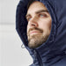 Men's Cascadia Thermal Jacket - A man wearing a navy thermal puffer jacket with a hood, featuring a logo on the chest.