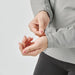 Women's Cascadia Thermal Jacket - A woman's hand adjusts the cuff of a light grey thermal jacket. The jacket features a fitted design with a logo.