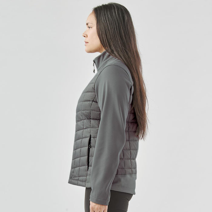 Women's Appalachian Thermal Softshell Jacket - A woman stands sideways wearing a grey Women's Appalachian Thermal Softshell Jacket. The jacket features a quilted design and a logo.