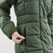 Women's Elkridge Parka - A green women's puffer jacket with a zipper pocket and quilted texture, featuring a person’s hand interacting with it.