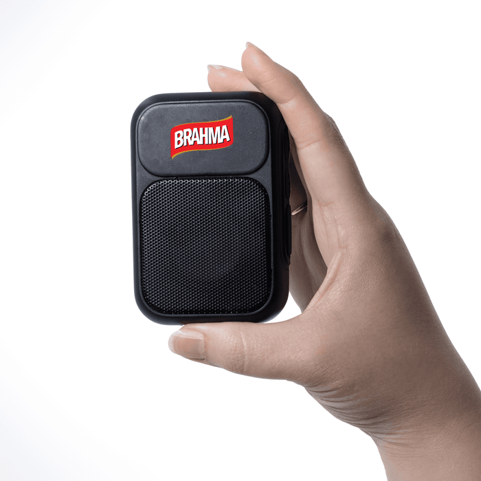 The Rebel Clip Speaker - A hand holding a small black speaker with a mesh front and a logo on top.
