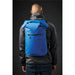 Cirrus Backpack - A blue backpack is worn on a person's back, featuring a front zipper pocket. The person is dressed in a black jacket.